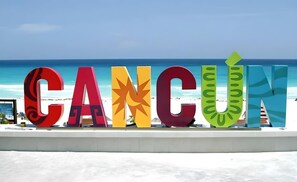 A large, colorful sign spelling 'CANCÚN' with a tropical leaf design on the letter 'N'. - Cancun Central Studio: Rooftop Terrace & Kitchen (CancÃºn)