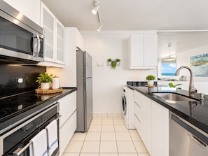 A modern kitchen with a microwave, oven, and washing machine.