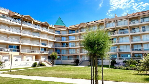 Ein mehrgeschossiges Hotel mit Balkonen, einem begrünten Dachgarten und einem gepflegten Rasen.