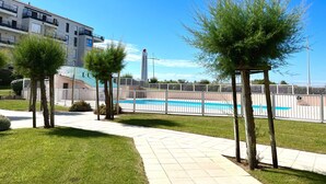 Ein Wohngebiet mit einem Schwimmbad, einem hohen Gebäude mit Balkonen und blauem Himmel.