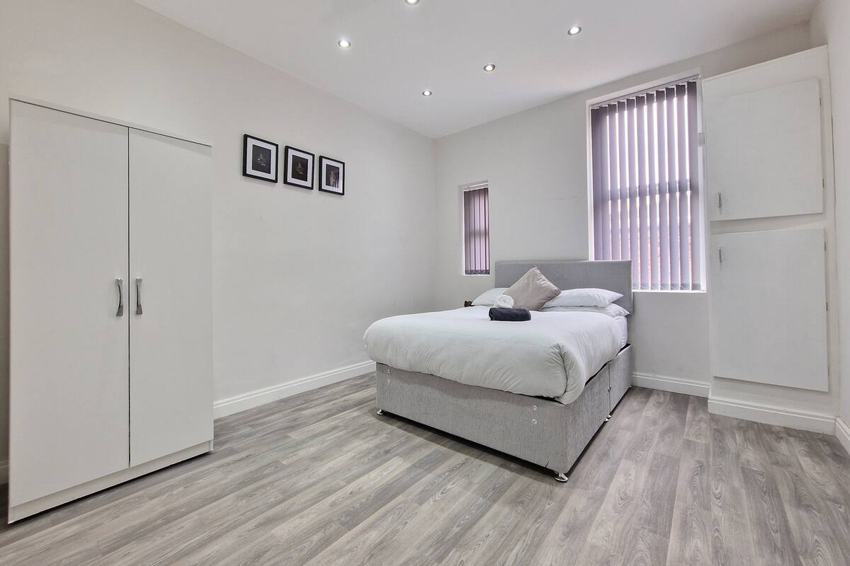 A bedroom with a bed, wardrobe, and a window with blinds.