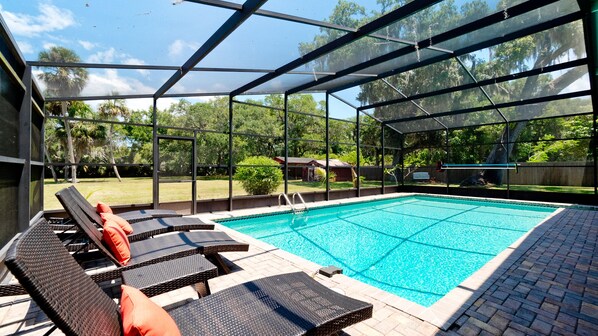 Una piscina exterior techada con sillas de descanso y vistas al entorno verde.