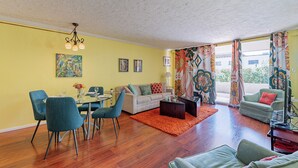 Una sala de estar con comedor, un sofá, una mesa de centro y un televisor.