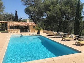 A rectangular swimming pool with a tiled deck, lounge chairs, a small structure with a tiled roof, and surrounding trees. - In a quiet, hilly setting, bright residence under the pine trees! (La Bouilladisse)