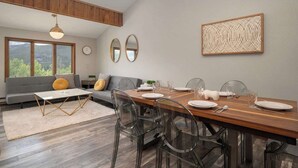 A modern dining area with a wooden table, clear chairs, and a gray sofa. - Amazing Views! Downtown Penthouse with Sauna (Winter Park)