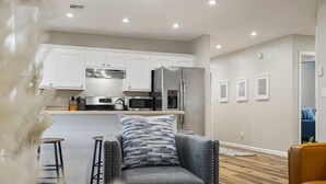 A modern kitchen with white cabinets, stainless steel appliances, and a bar area. - Tranquil TU Getaway! EXPO/Route 66/Cherry St -3bd (Tulsa)
