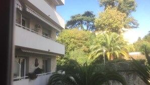 Un immeuble à plusieurs étages doté de balcons, entouré d’une végétation luxuriante et d’arbres.
