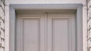 Uma porta dupla com design de painel retangular, um olho de fechadura e uma maçaneta.