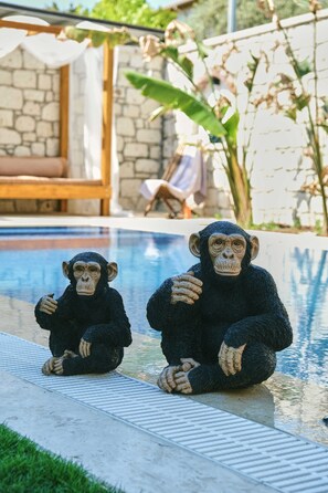 Two chimpanzee statues sitting by a poolside.