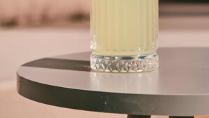Um copo transparente com canudo sobre uma mesa redonda.