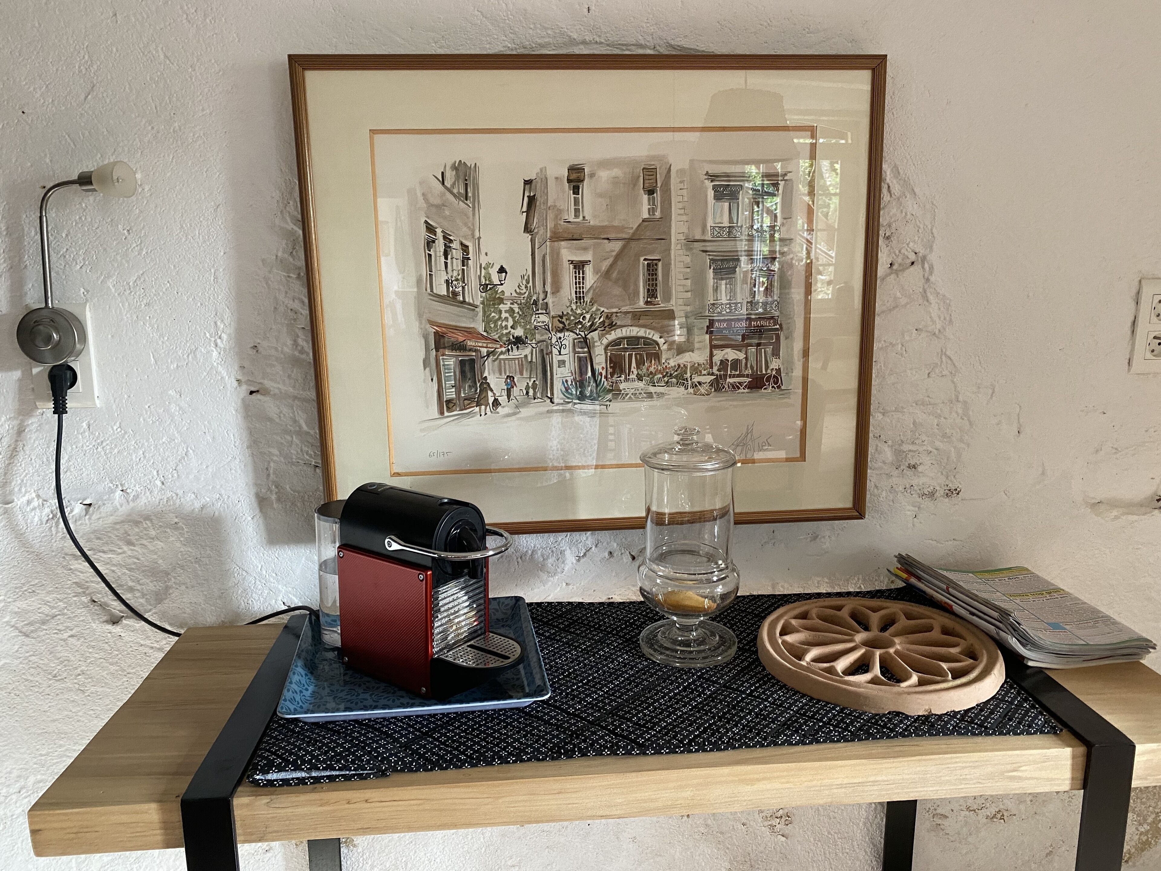 A table with a vintage camera, a glass jar, and a decorative plate.