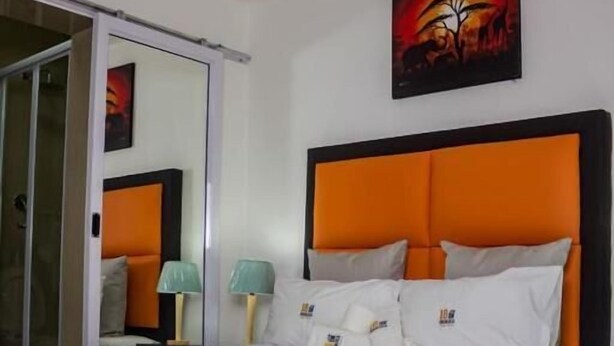 Une chambre d’hôtel avec un grand lit, une porte coulissante, un tableau au mur et une table de chevet avec une lampe.
