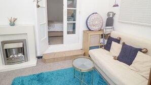 Ein gemütlicher Wohnbereich mit einer Couch, einem kleinen runden Tisch, einem Kamin und einer Tür zum Schlafzimmer.