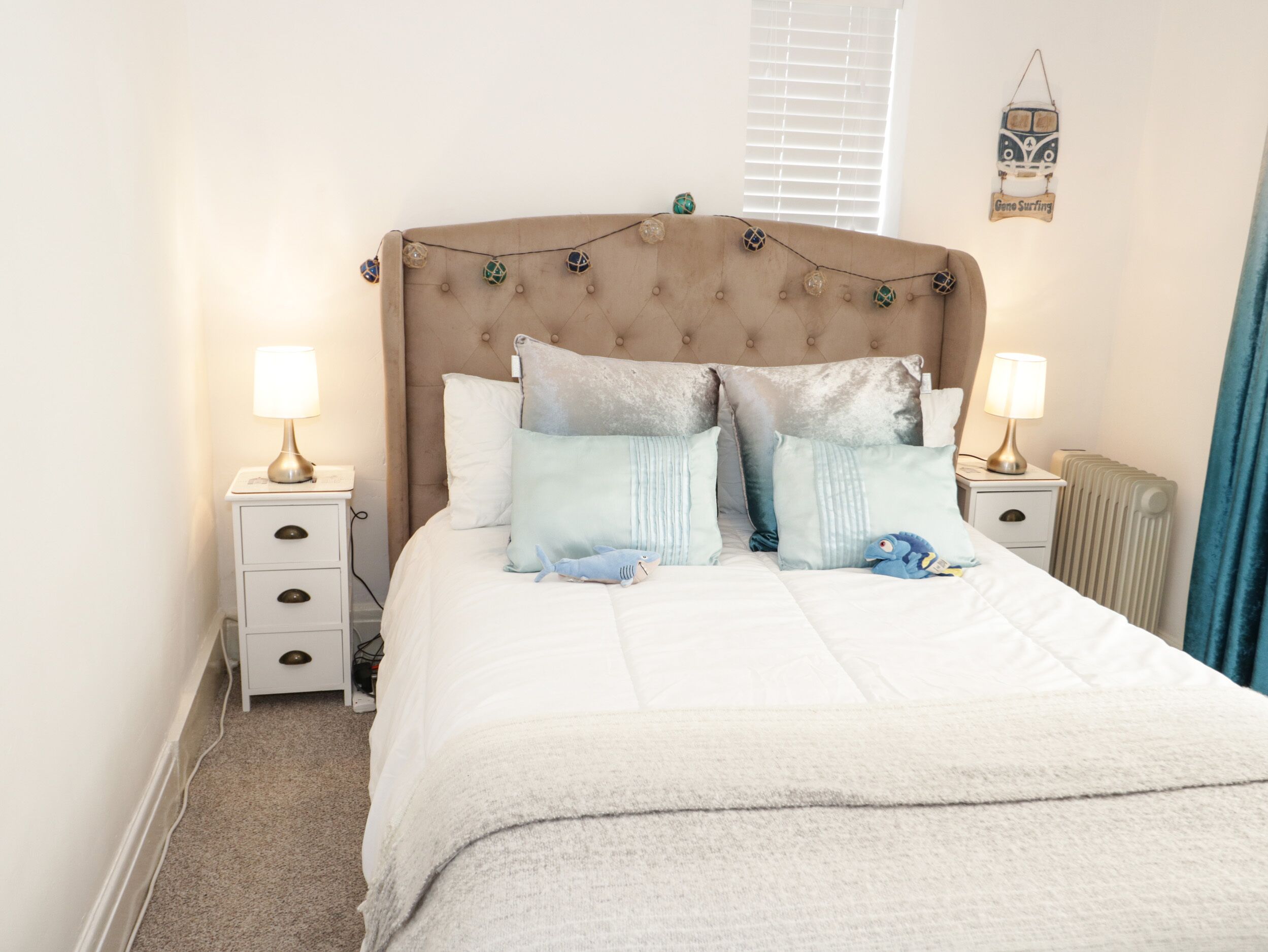 A neatly made bed with a tufted headboard, two bedside tables with lamps, and a wall decoration.