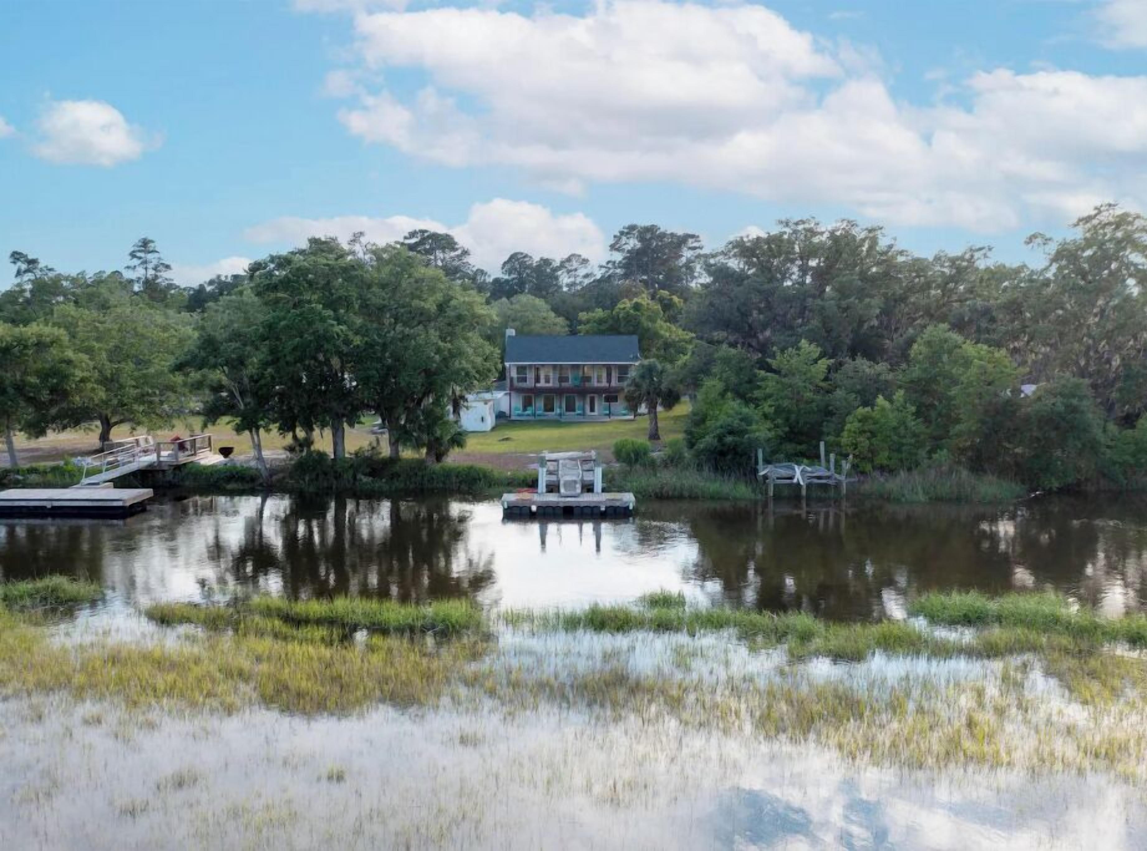 Una casa junto al lago, con un muelle y un bote pequeño.