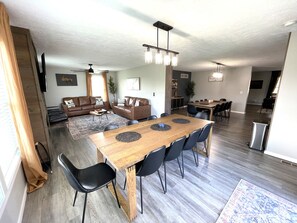Ein geräumiger Wohnbereich mit Esstisch, Sofas und Deckenventilator.