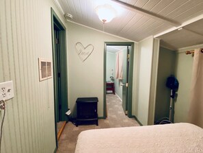 Un dormitorio con cama, un calefactor, un calefactor de pared y un ventilador de techo.