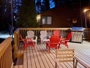 Una terraza de madera con mobiliario exterior y una parrilla.