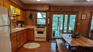 A wooden cabin kitchen with a refrigerator, stove, and wooden cabinets.