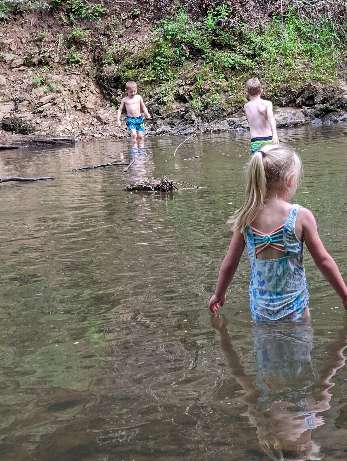 Un cadre naturel en plein air, avec une rivière, un terrain rocheux et une végétation luxuriante.