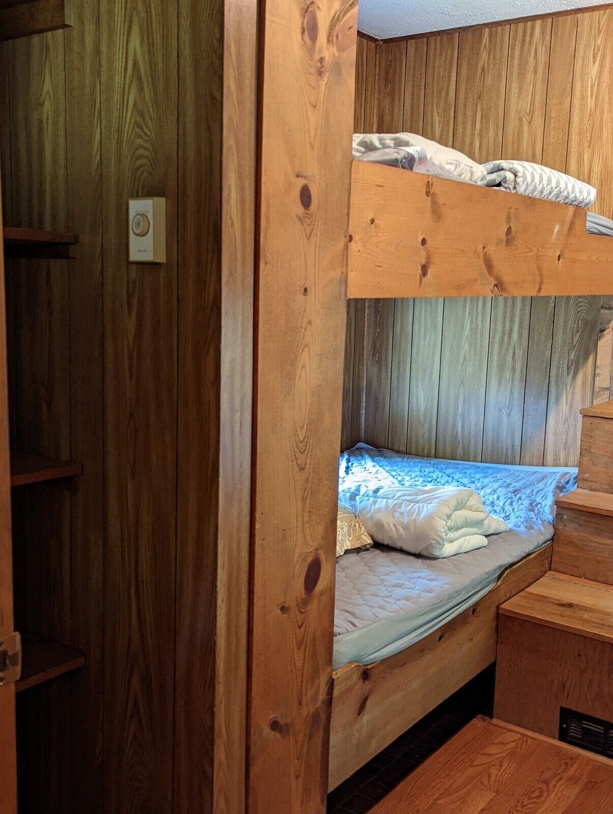 A bunk bed with a wooden headboard and a small desk area.