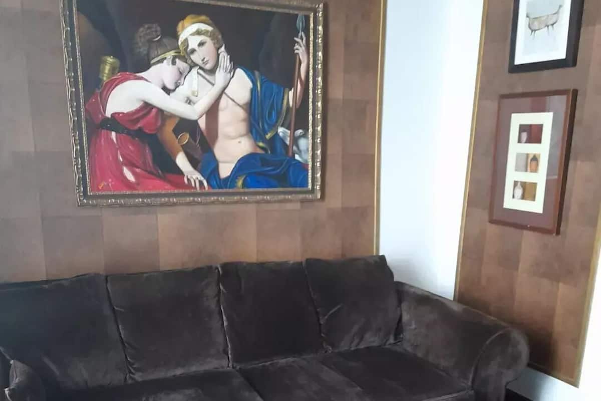 A dark-colored sofa, a wooden coffee table with a decorative object, and a framed painting on the wall.