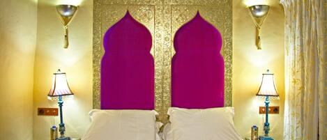 A room with a bed, two nightstands, and a decorative wall with a golden pattern and two purple arch-shaped panels.