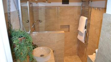 Une petite salle de bain fermée, dotée d’une douche en verre, d’un lavabo rond et d’un porte-serviettes.