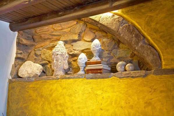 Una pared de piedra con un estante que contiene libros y objetos decorativos.