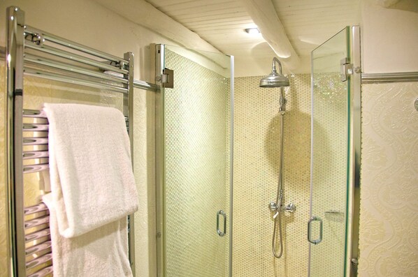 A glass-enclosed shower with a handheld showerhead, a glass door, and a towel rack with a white towel. - Casa pinto (Reguengos de Monsaraz)