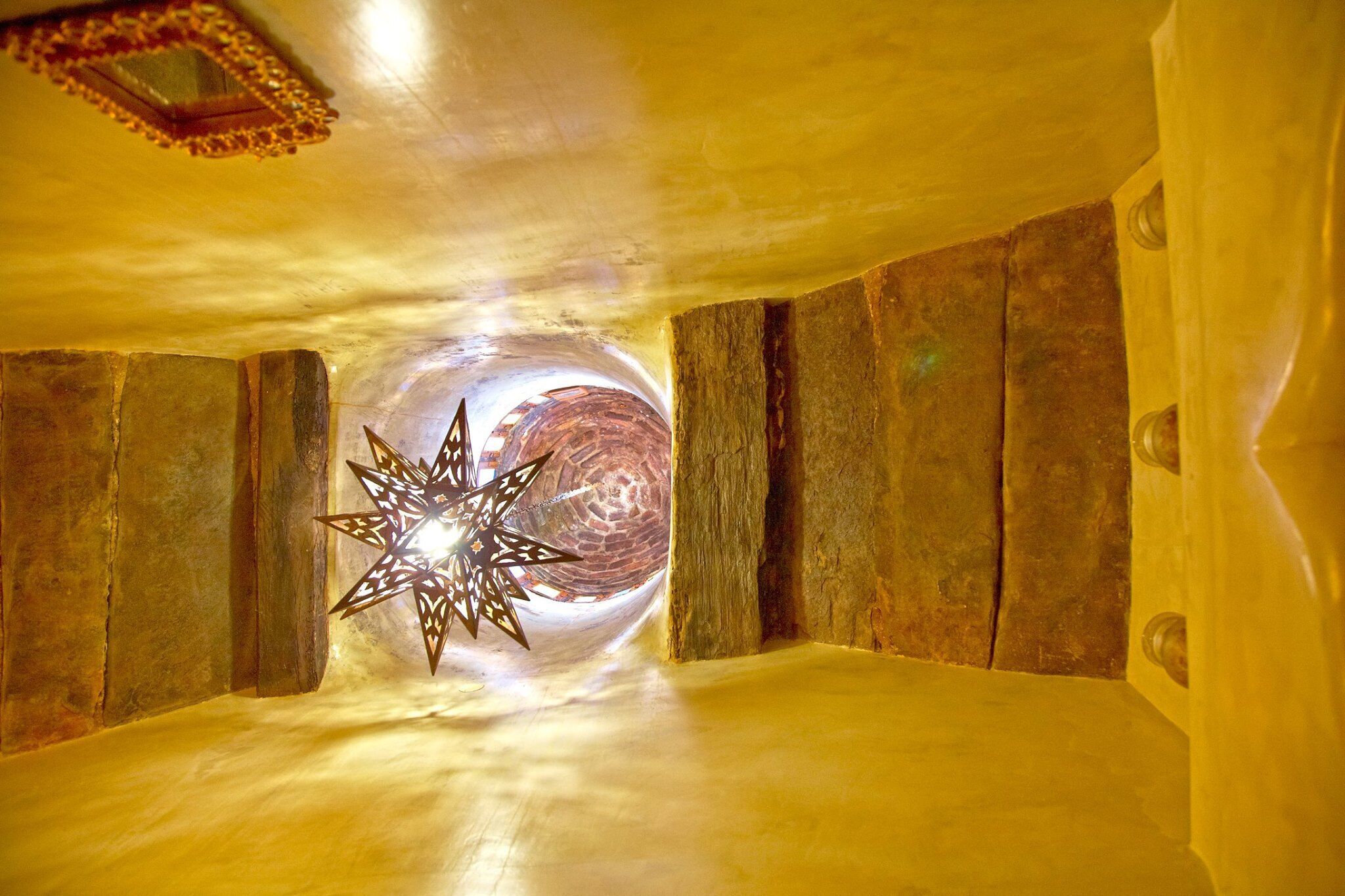 A room with a star-shaped light fixture, wooden walls, and a textured ceiling.
