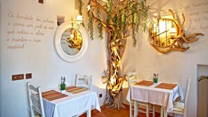 A dining area with two tables, chairs, and a wall-mounted tree sculpture. - Casa pinto (Reguengos de Monsaraz)