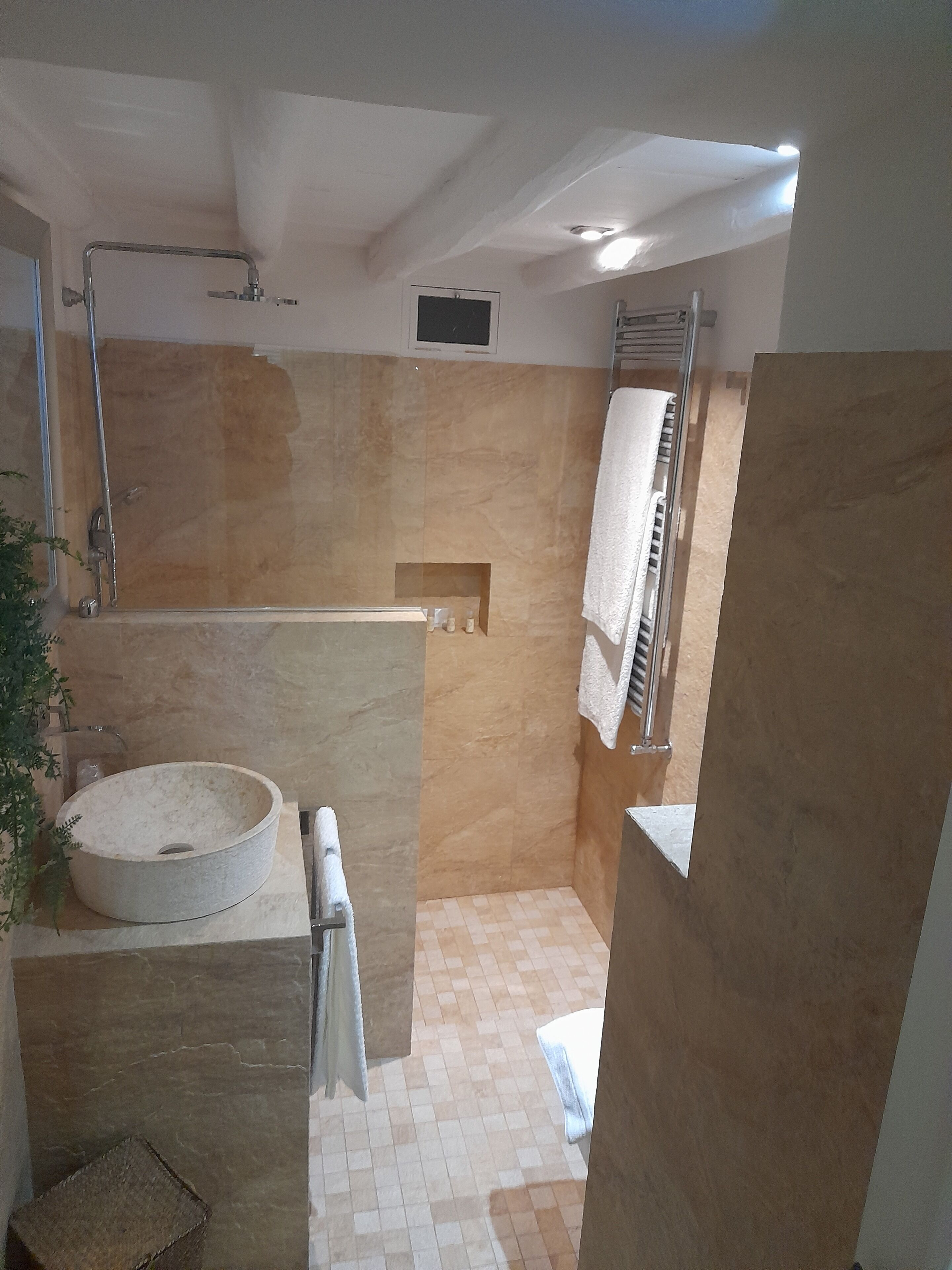 Un baño moderno con un lavamanos de piedra, una cabina de ducha de vidrio y un perchero para toallas.