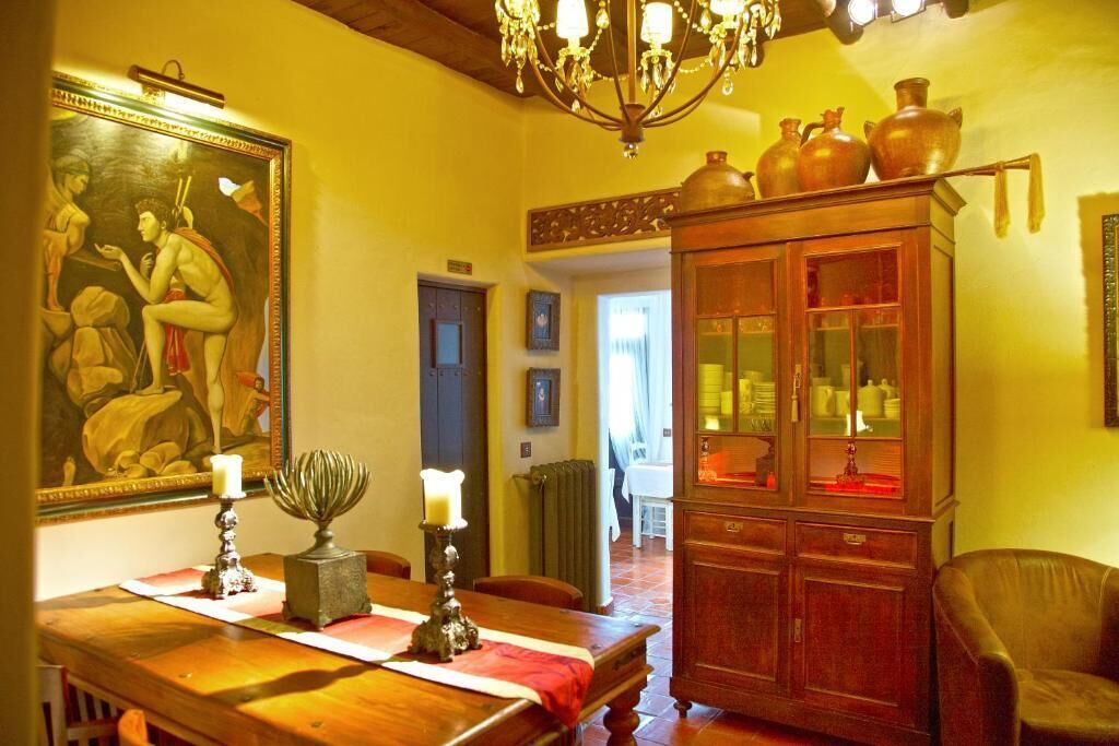 Un coin repas avec une table en bois, des bougies et un tableau au mur.