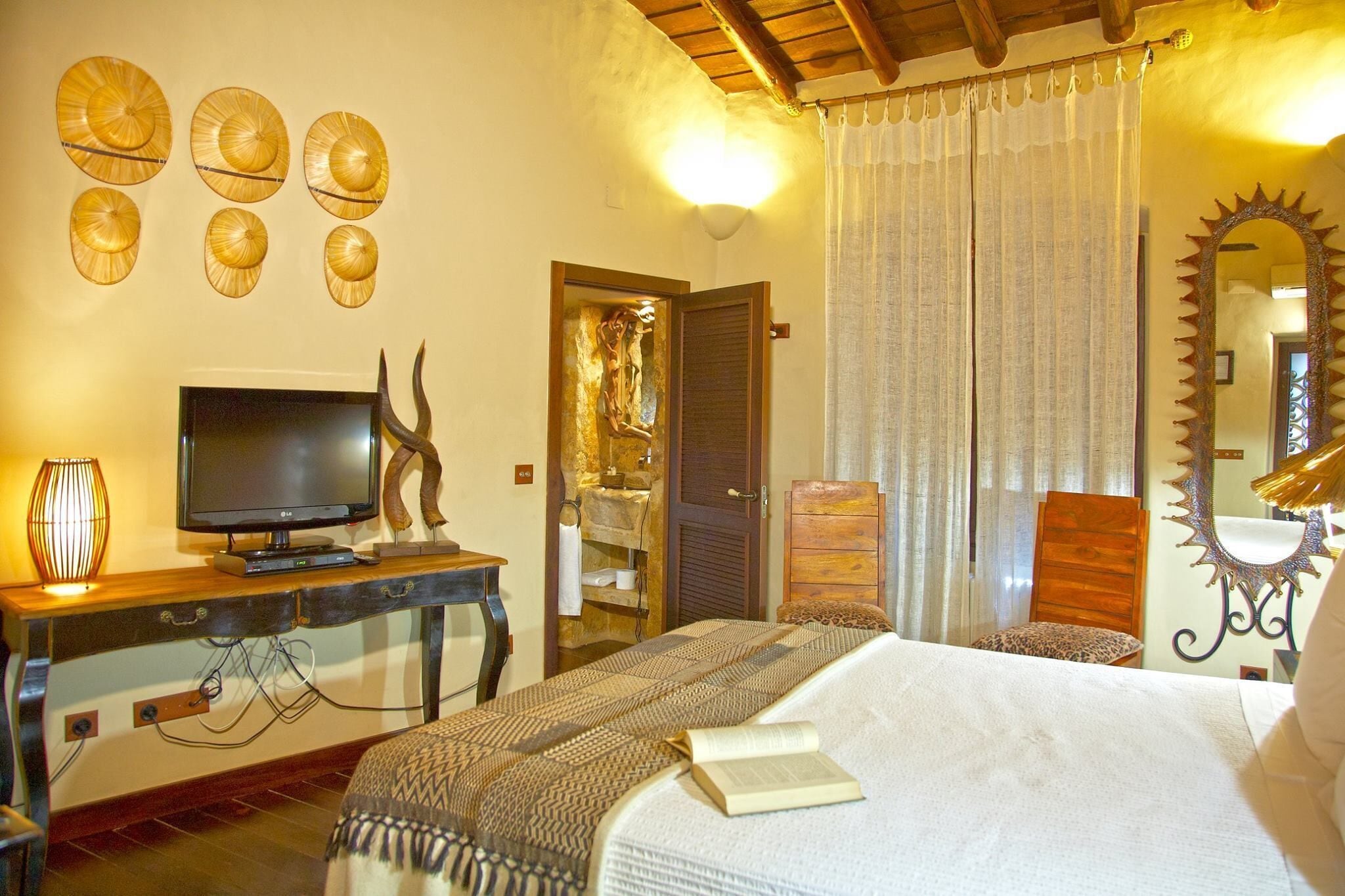 Un dormitorio con cama, televisión, escritorio y espejo.