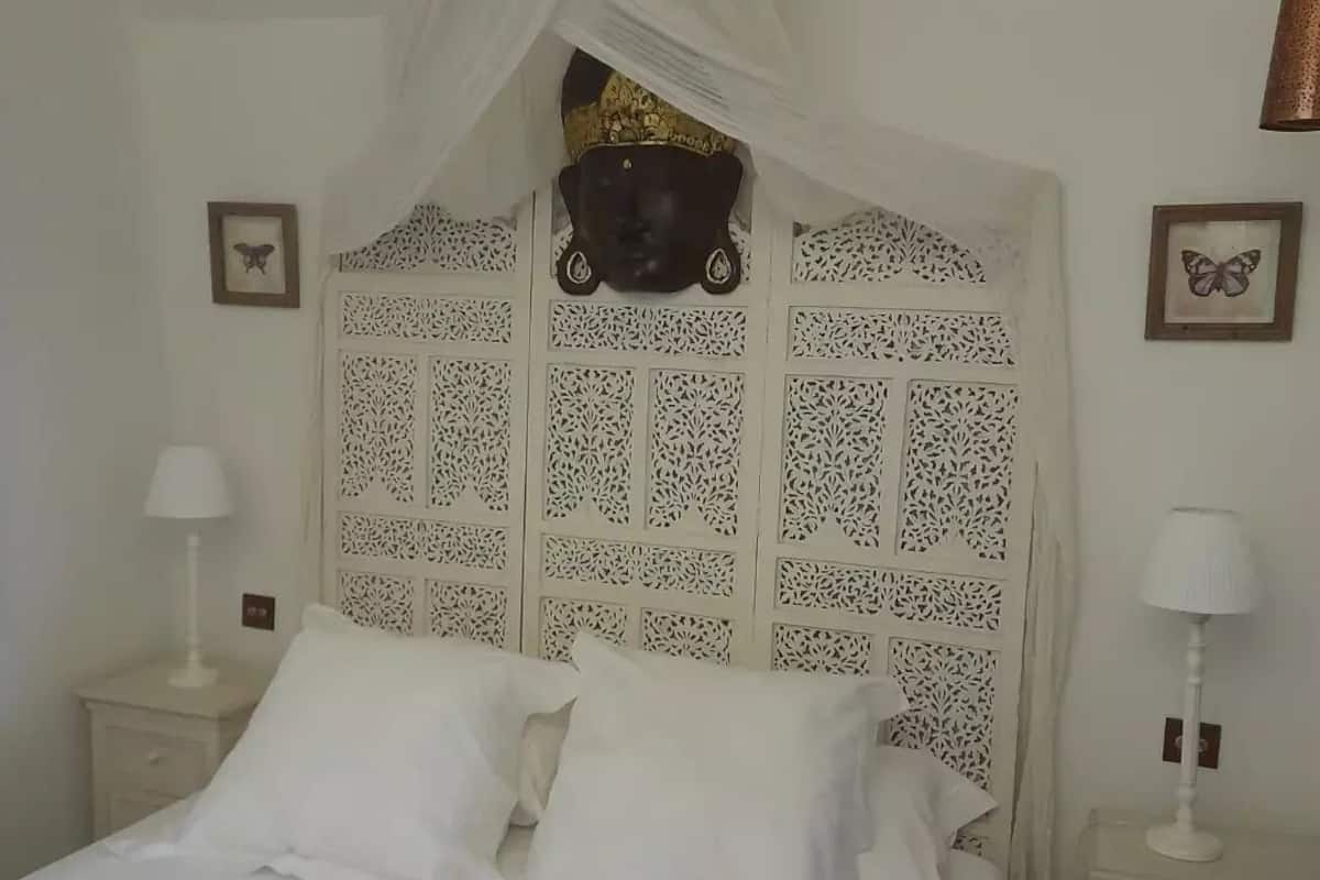 A bed with a canopy, two bedside tables, and a decorative headboard with a carved design.