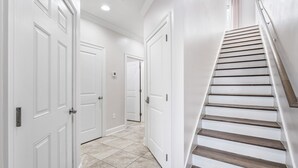Un pasillo con puertas blancas y una escalera de madera.