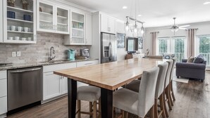 Una cocina moderna con armarios blancos, una mesa de comedor de madera y un horno empotrado.