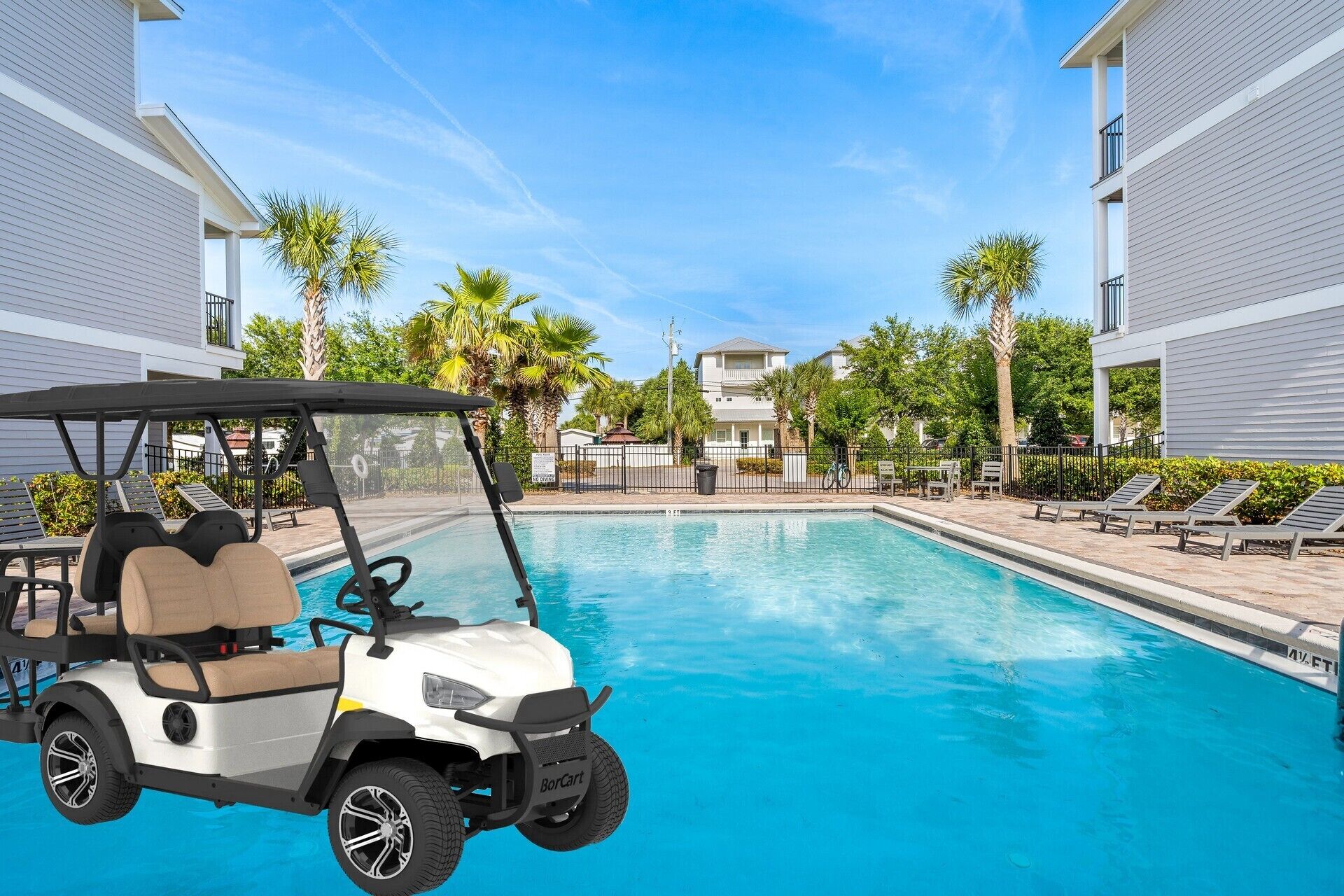 A golf cart parked by a swimming pool with lounge chairs and palm trees in the background.