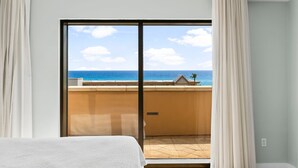 Ein Zimmer mit einer großen Schiebeglasdoor, die auf einen Balkon mit Meerblick führt.