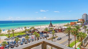 Un paysage urbain côtier avec une plage, des voitures garées et des bâtiments.