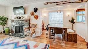 A cozy living room with a stone fireplace, wooden dining table, and comfortable seating.