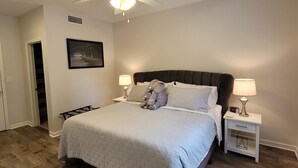 A bedroom with a bed, two bedside tables, a ceiling fan, a nightstand, a framed picture, and a door. - Walk to Stadium/Strip/Downtown! 2 bd/2 bath, Off-street parking! (Tuscaloosa)