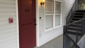 A house entrance with a red door, a welcome mat, a fire alarm, a ceiling fan, and a staircase. - Walk to Stadium/Strip/Downtown! 2 bd/2 bath, Off-street parking! (Tuscaloosa)