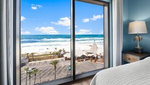 Camera d'albergo con una grande finestra che si affaccia sulla spiaggia e sull'oceano.