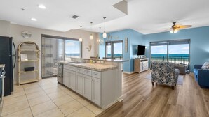 Amplia sala de estar con cocina, un balcón con vistas y un ventilador de techo.