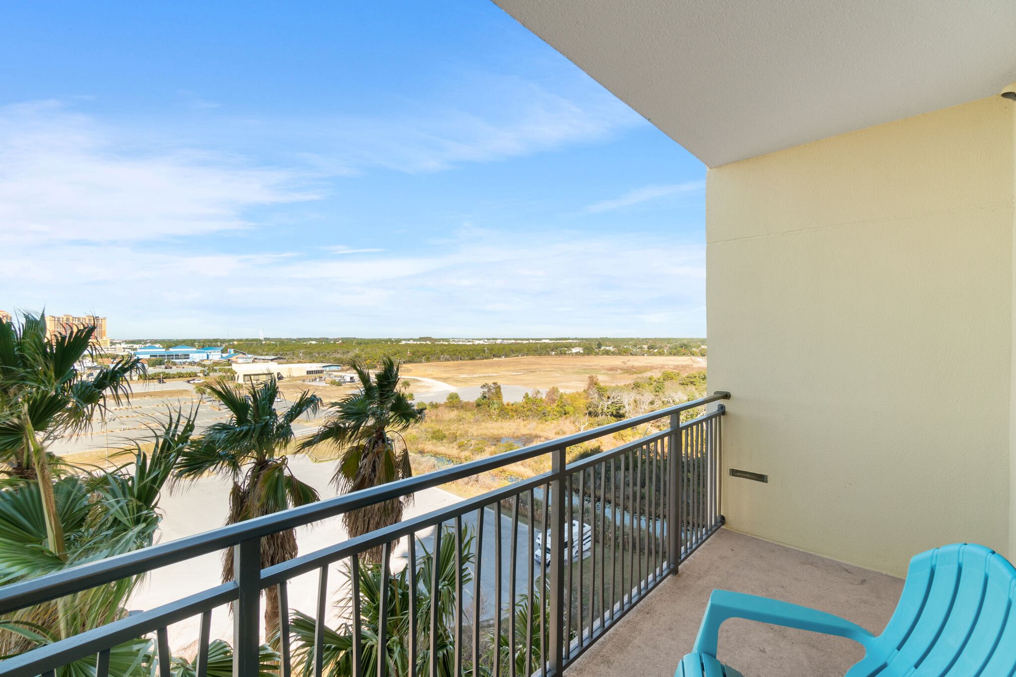 A balcony with a view of a beach and palm trees.