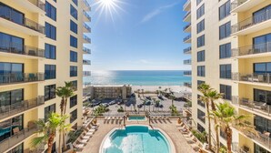 Un hotel de gran altura con piscina central, balcones y vistas a la playa.