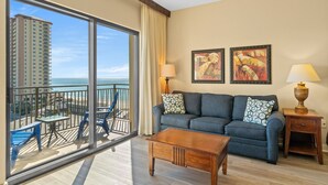 A hotel room with a balcony, a sofa, a coffee table, and two lamps. - Origin 0833 - Studio King - Sunrise & Gulf View (Panama City Beach)