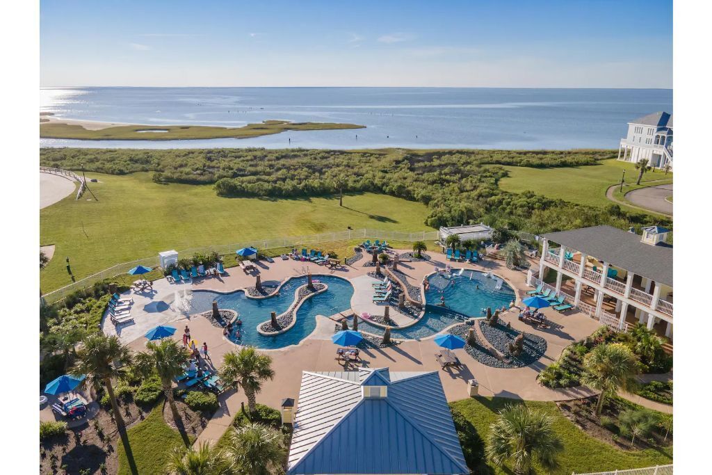Resort com ampla área de piscina, praia e vista para o oceano.
